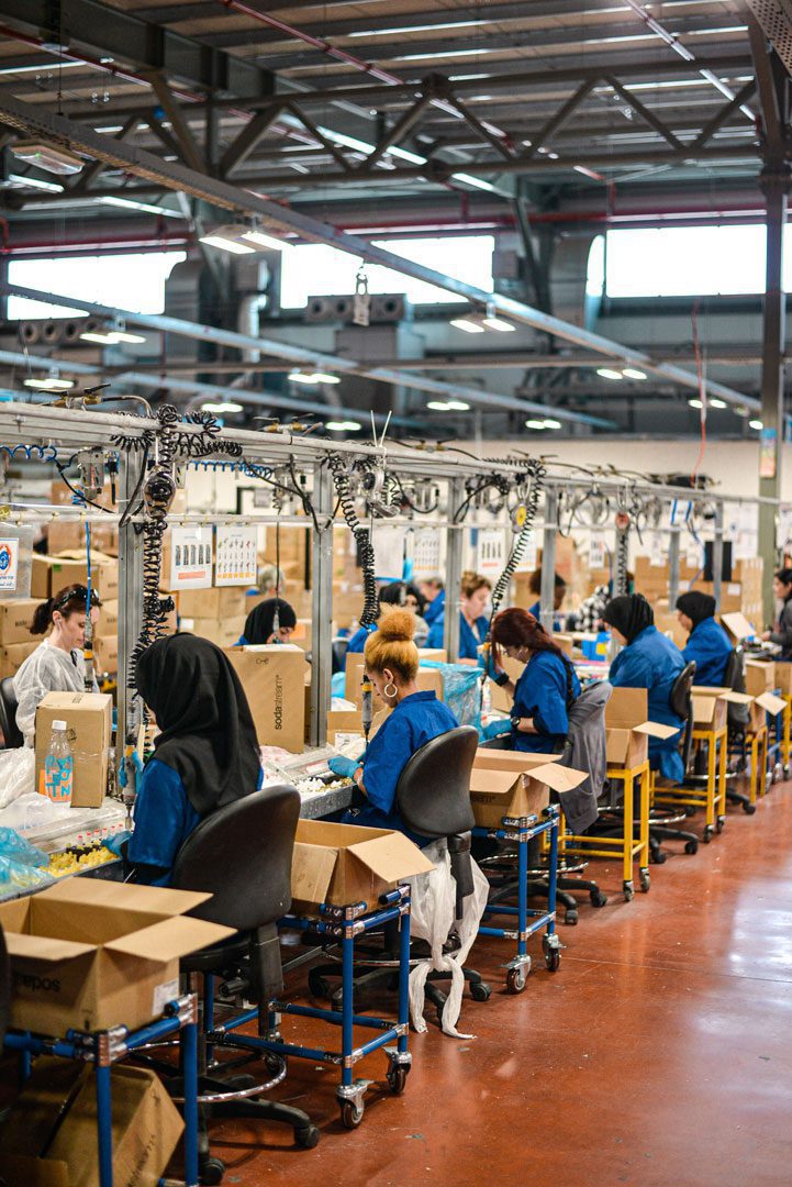 manufacturing workers working on new products in booths in a factory